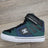 Green and blue sneaker with white sole on a wooden floor